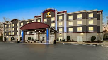 A hotel with a prominent 'Comfort Suites' sign, a covered entrance, and a parking lot.
