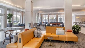 A spacious lobby with a large seating area, a bar, and a dining area. - Hilton Garden Inn Charlotte/Concord (Concord)
