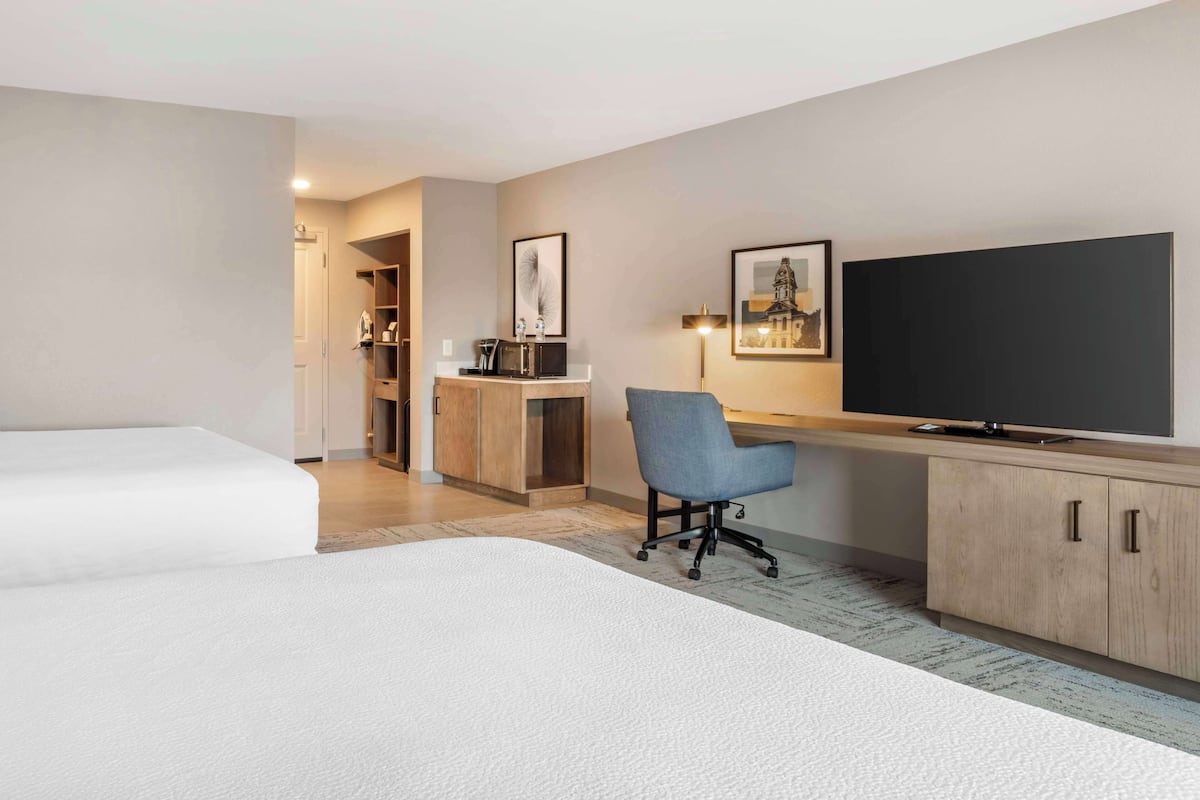 A hotel room with a bed, a desk with a chair, a TV, and a wardrobe.