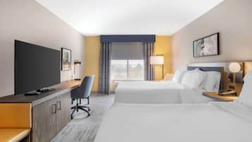 A hotel room with a bed, a desk, a chair, a TV, and a window with curtains.