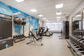 A gym with exercise equipment, treadmills, and dumbbells.