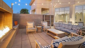 An outdoor patio with a fire feature, seating area, and string lights. - Hilton Garden Inn Charlotte/Concord (Concord)