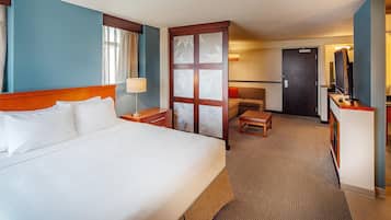 Une chambre d’hôtel avec un grand lit, un bureau, une chaise, une télévision et une porte.