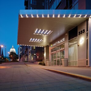 L'ingresso di un hotel dal design moderno, con insegne illuminate e una vista chiara sulla strada.