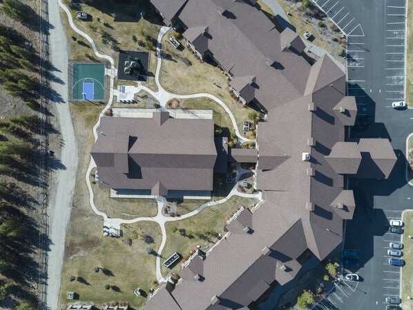 An aerial view of a residential area with a large building, parking lot, and a basketball court.
