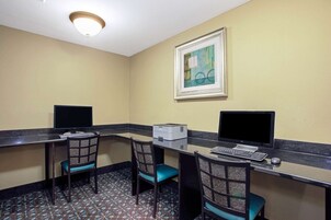 Una piccola area ufficio con due scrivanie, ciascuna dotata di computer e stampante. Sono presenti due sedie con rivestimenti decorati. Un'opera d'arte incorniciata è appesa al muro sopra le scrivanie.