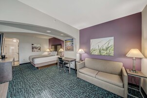 Ein Hotelzimmer mit einem Bett, einem Schreibtisch, einer Couch und einem Esstisch.