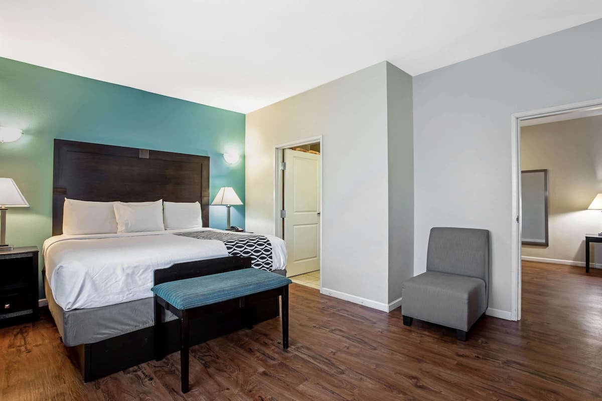 Une chambre d’hôtel comprenant un lit, une table de chevet, une lampe, un banc et une chaise.