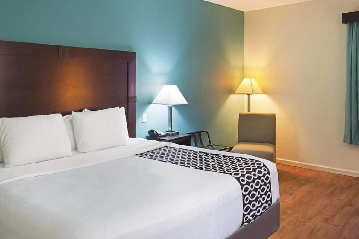 Une chambre d’hôtel avec un grand lit, deux tables de chevet, une chaise et un bureau.