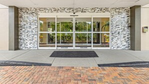A building entrance with a glass door, a stone wall, and a brick pathway. - Quality Inn & Suites Tampa near Fairgrounds and Casino (Tampa)
