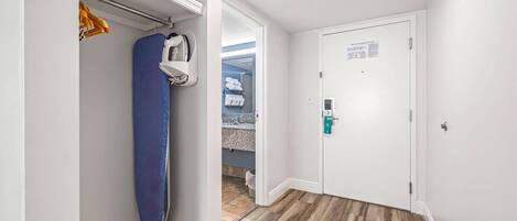 A hallway with a wooden floor, a white door with a green sign, and a blue shower curtain.