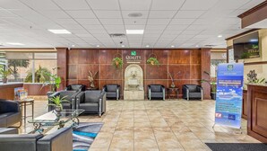 A hotel reception area with a reception desk, several seating areas, a fountain, and a signboard. - Quality Inn & Suites Tampa near Fairgrounds and Casino (Tampa)