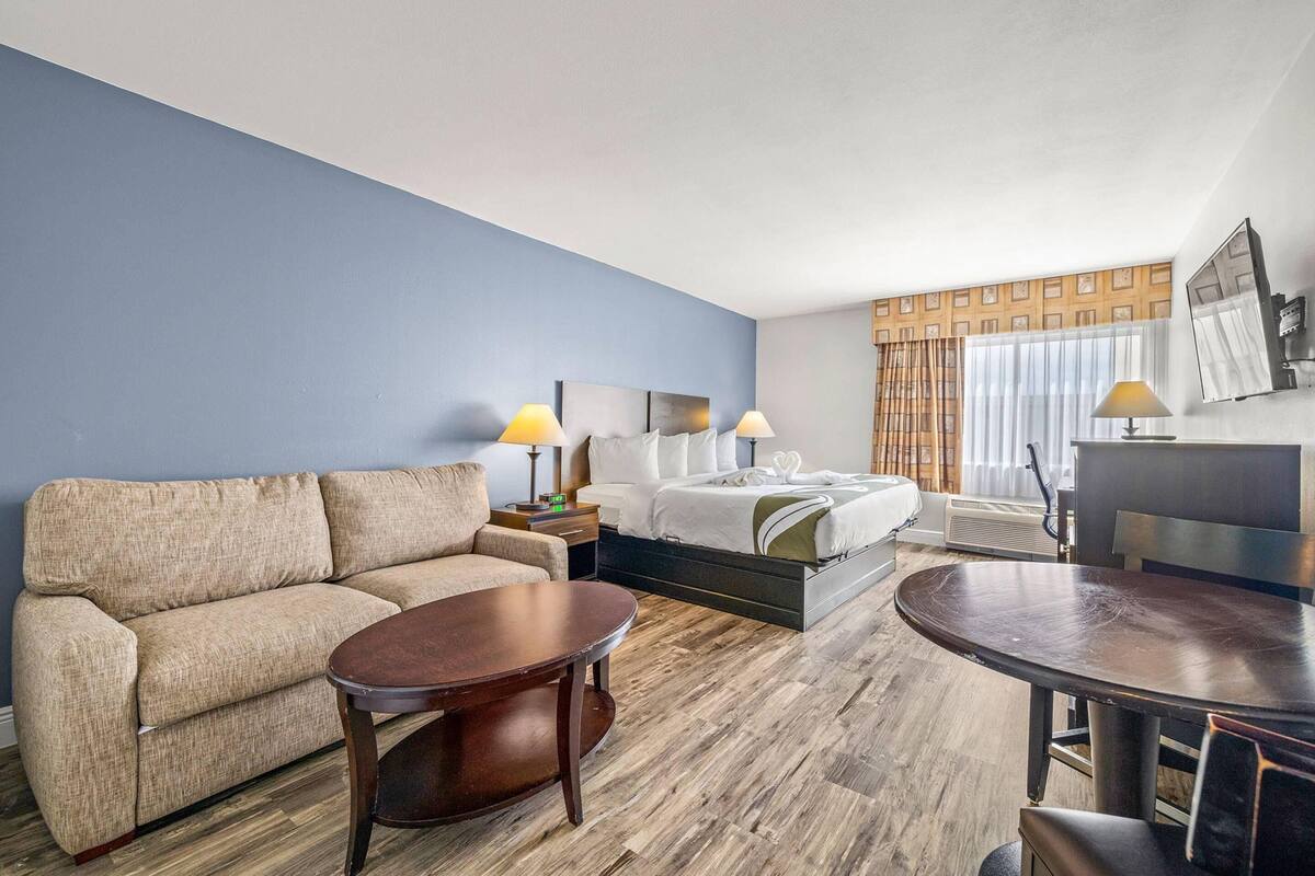 A hotel room with a sofa, a bed, a round table, and a desk.