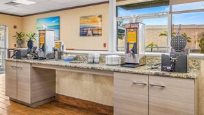 A kitchen area with a granite countertop, coffee machines, waffle maker, and a view of the outside. - Quality Inn & Suites Tampa near Fairgrounds and Casino (Tampa)