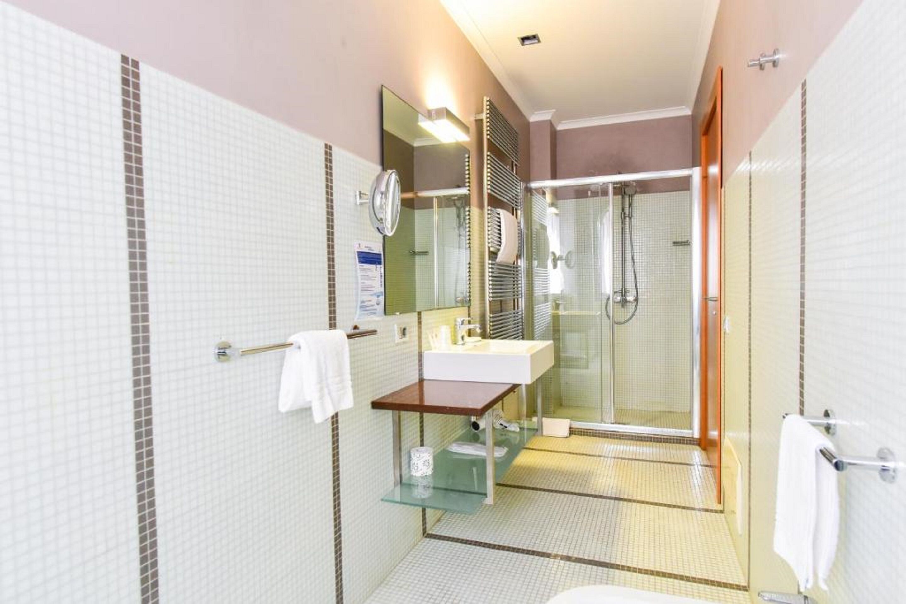 Un bagno moderno con cabina doccia in vetro, lavabo con specchio e WC.