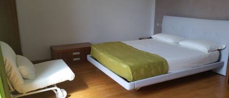 Une chambre à coucher avec un lit, une chaise, une table de chevet et un plancher en bois.