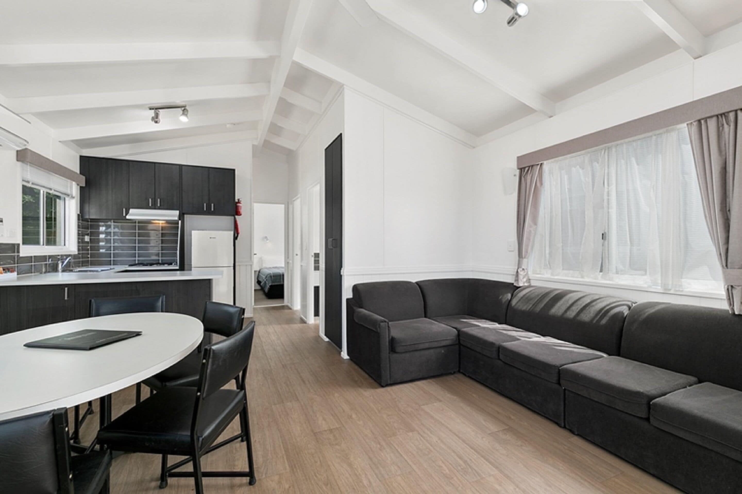 Un salon moderne et bien éclairé, comprenant une cuisine, une table à manger et un grand canapé.