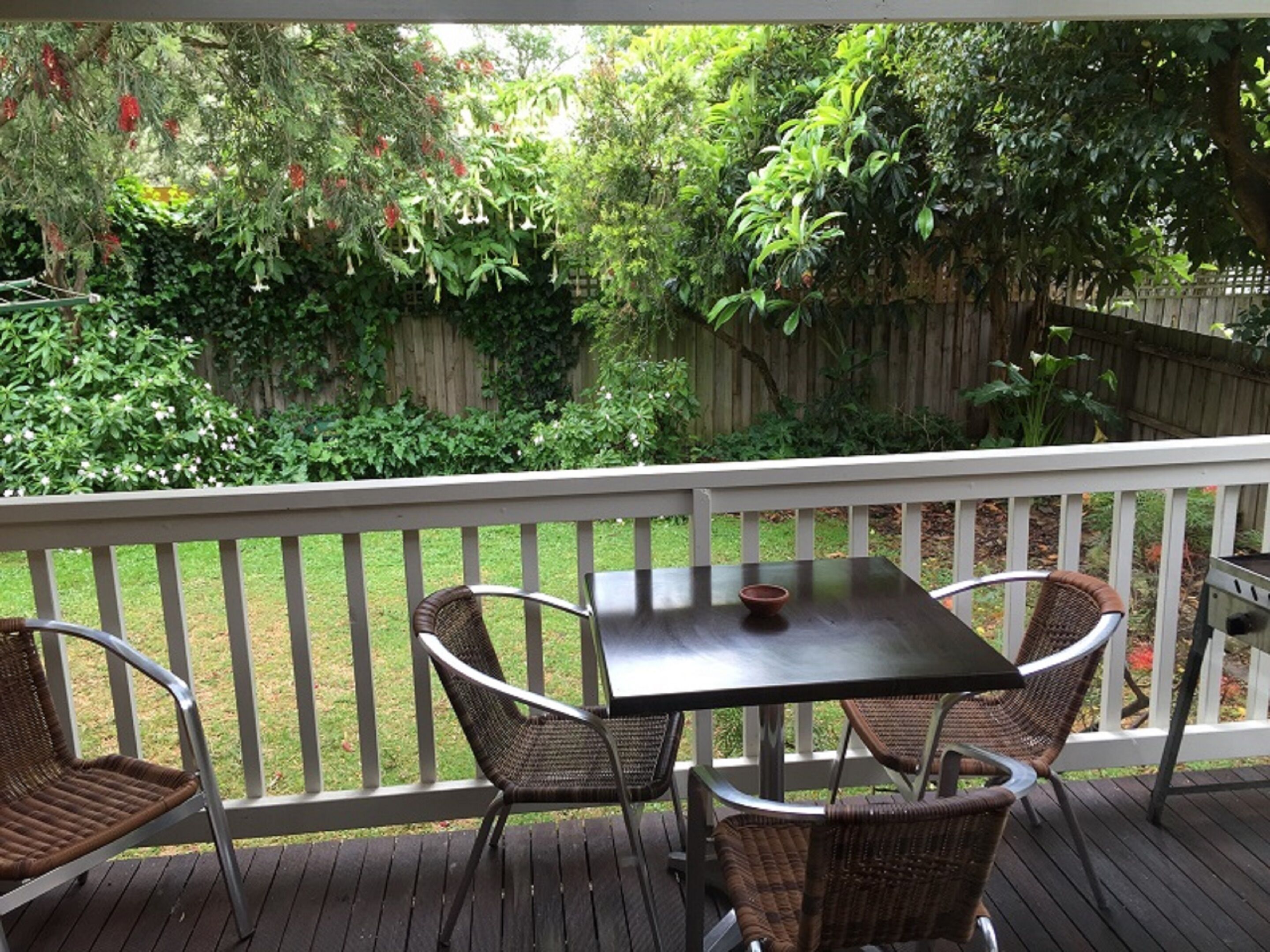 A covered patio with a table and four wicker chairs.
