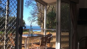 A balcony with a table and chairs, a view of the sea, and a door with a glass panel. - Kaloha Holiday Resort (Cowes)