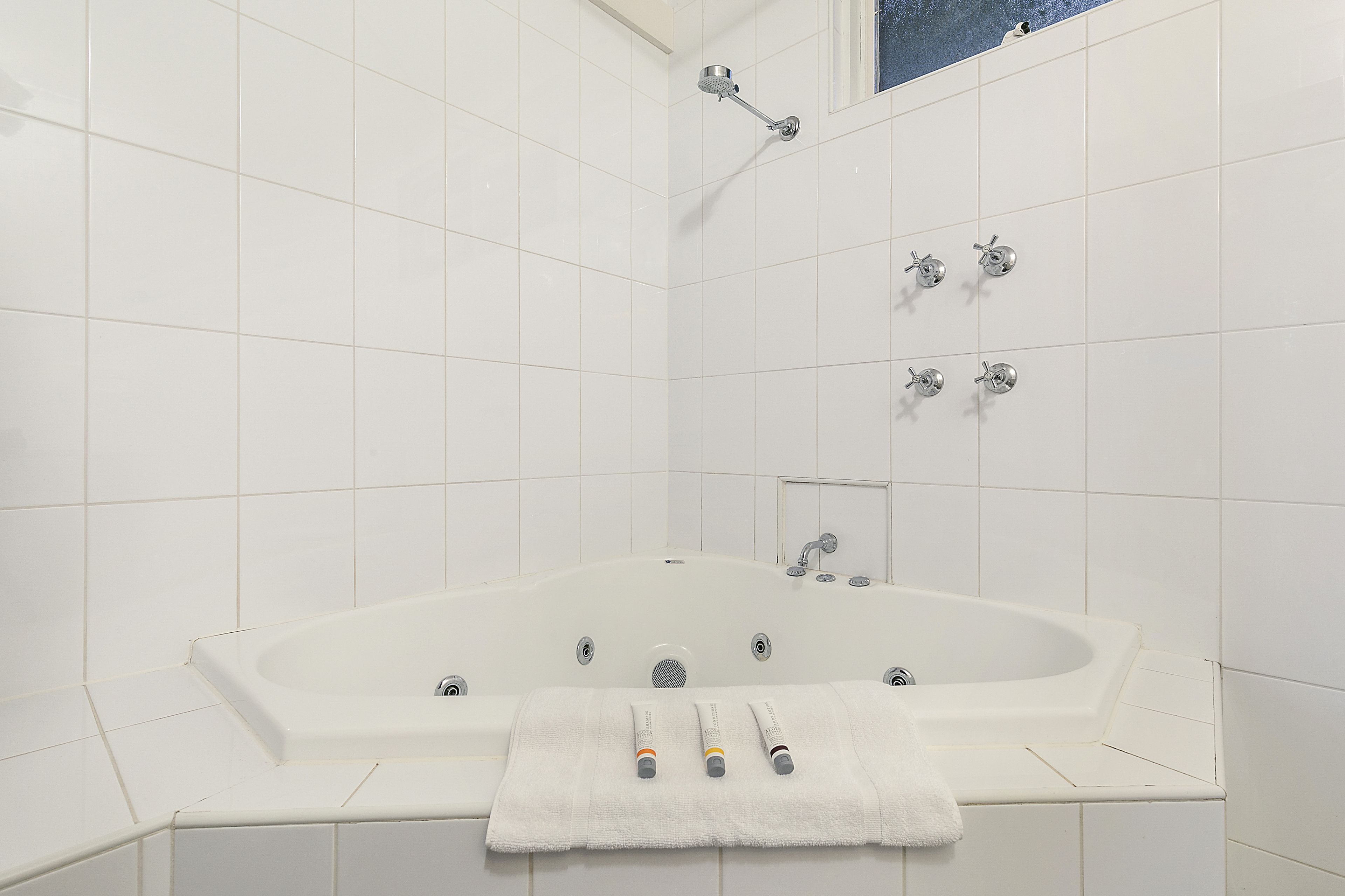 Une salle de bain moderne dotée d’une grande baignoire, d’une douche et de plusieurs robinets.