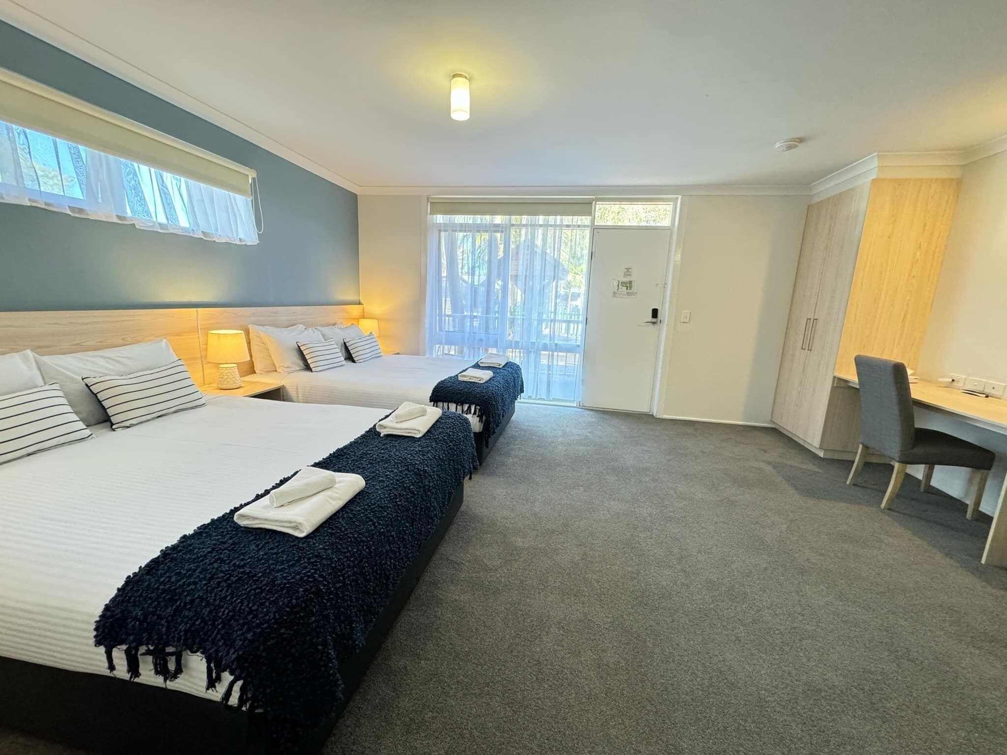 A hotel room with two beds, a desk, and a wardrobe.