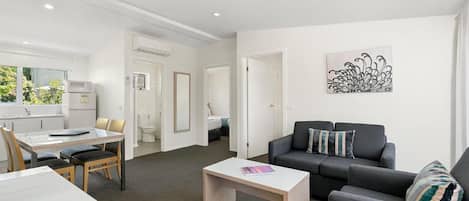 En moderne stue med en grå sofa, et hvidt sofabord og et spiseområde med et hvidt bord og stole.