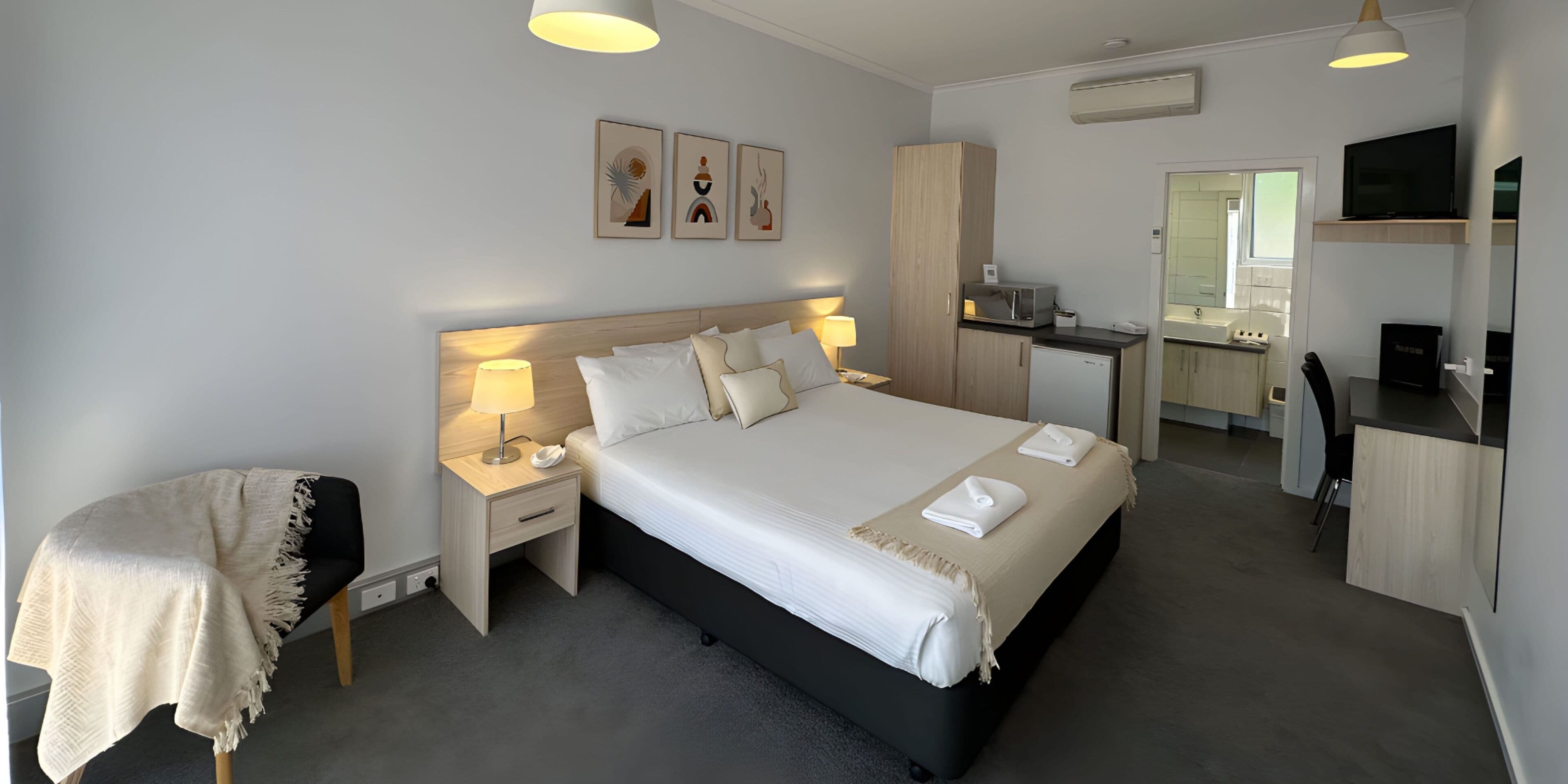 A modern hotel room with a large bed, bedside tables, a desk, and a television.