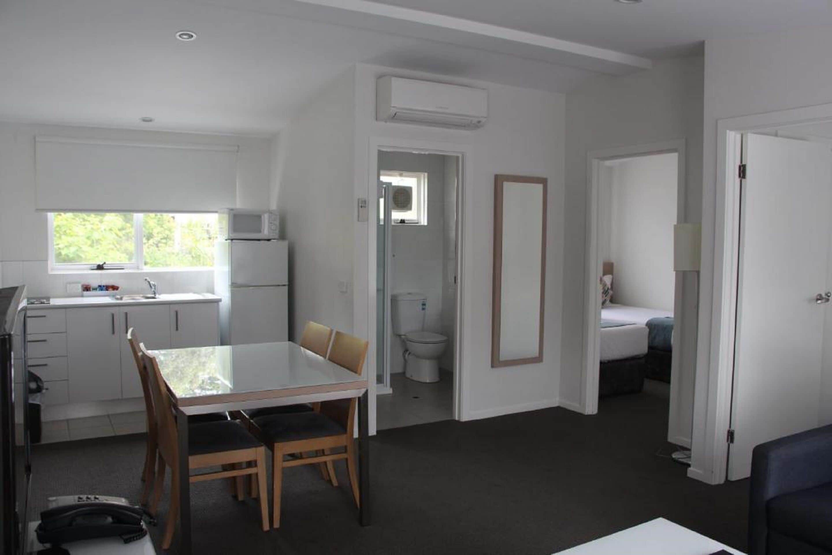 Un espace de vie compact comprenant un coin cuisine, un coin repas, une salle de bain et une chambre.