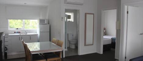 Un espace de vie compact comprenant un coin cuisine, un coin repas, une salle de bain et une chambre.