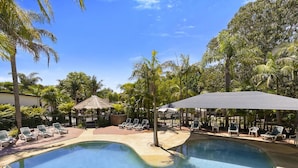 A pool area with lounge chairs and a thatched-roof structure. - Kaloha Holiday Resort (Cowes)