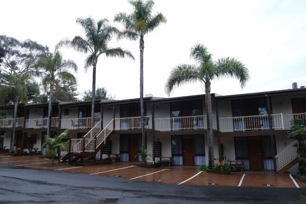 A row of motel buildings with balconies and a parking lot.