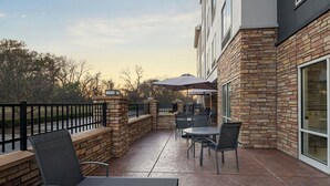 A patio area with outdoor seating, stone walls, and a view of the surrounding landscape. - Fairfield Inn & Suites Tulsa South Medical District (Tulsa)
