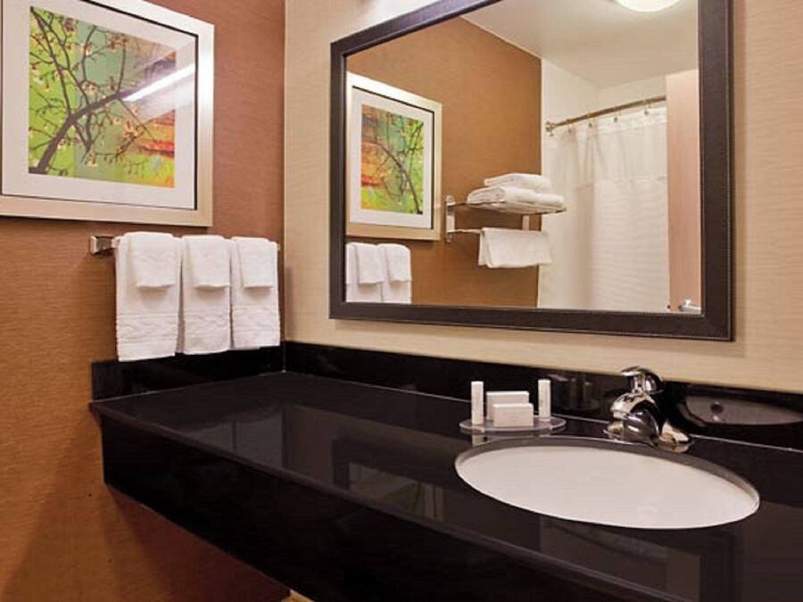 A bathroom with a black countertop, a white sink, and two framed pictures on the wall.