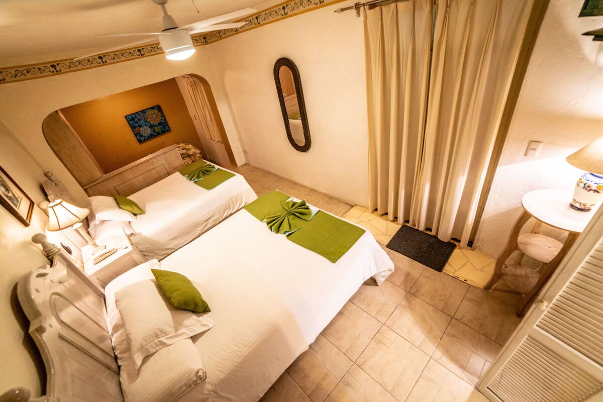 A hotel room with two beds, a bathroom, and a small sitting area.