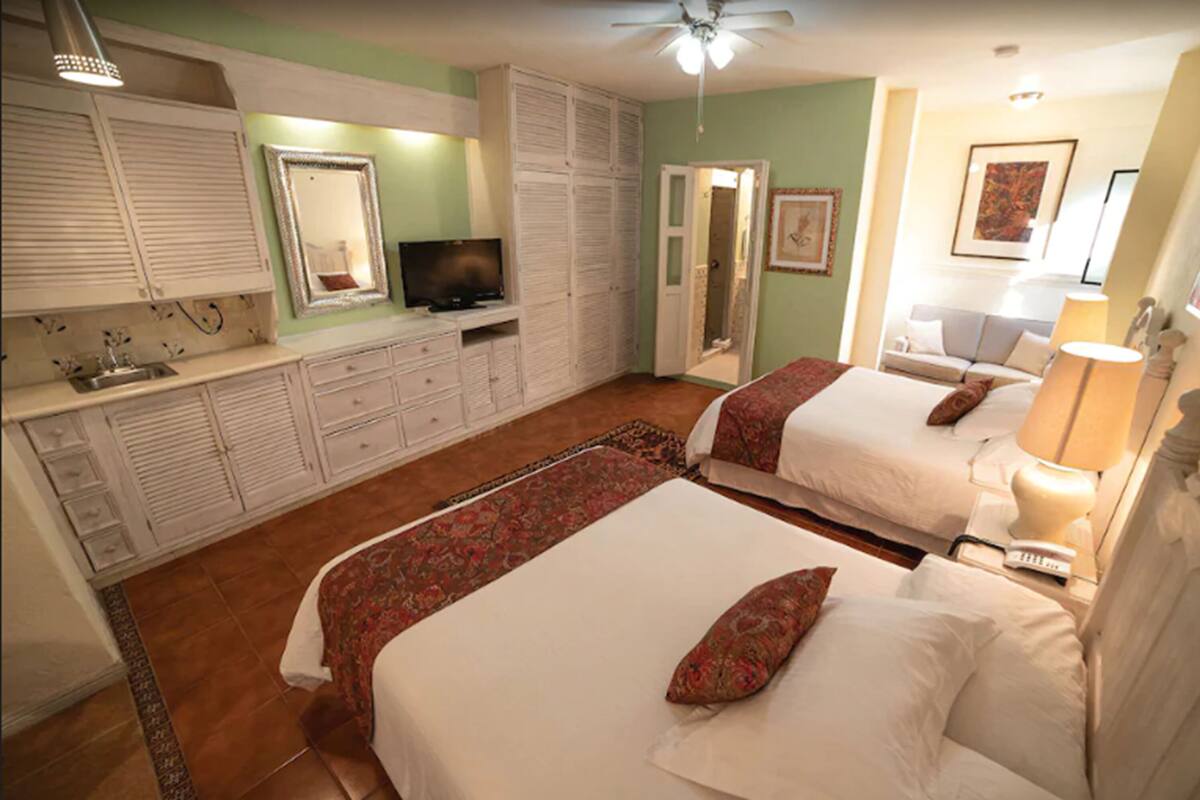 A bedroom with two beds, a television, a wardrobe, and a bathroom.