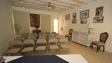 A room with a dining table, chairs, a white dresser, and framed pictures on the wall.