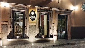 A building with three entrances, each with a metal gate and a small porch. There is a sign above the left entrance with illuminated text. - Villa Mirasol Hotel (San Miguel de Allende)