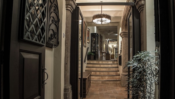 A hallway with a stone floor, a staircase, and a large plant. - Villa Mirasol Hotel (San Miguel de Allende)