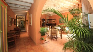 An interior with a dining area, wooden furniture, potted plants, and a tiled floor. - Villa Mirasol Hotel (San Miguel de Allende)