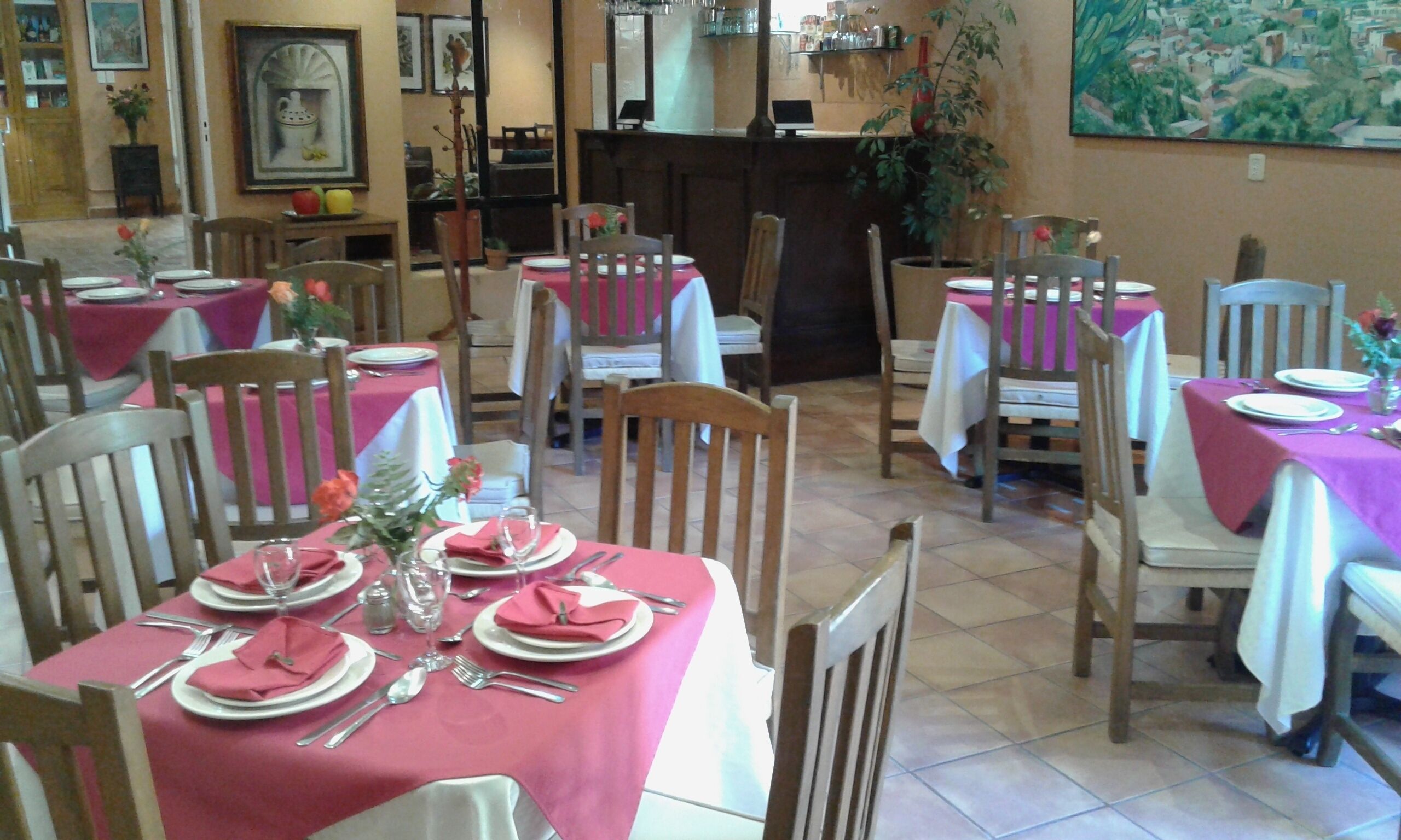 Un restaurante con mesas dispuestas para comer, sillas y una zona de bar.