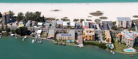 An aerial view of a coastal hotel area with multiple buildings, a beach, and boats.