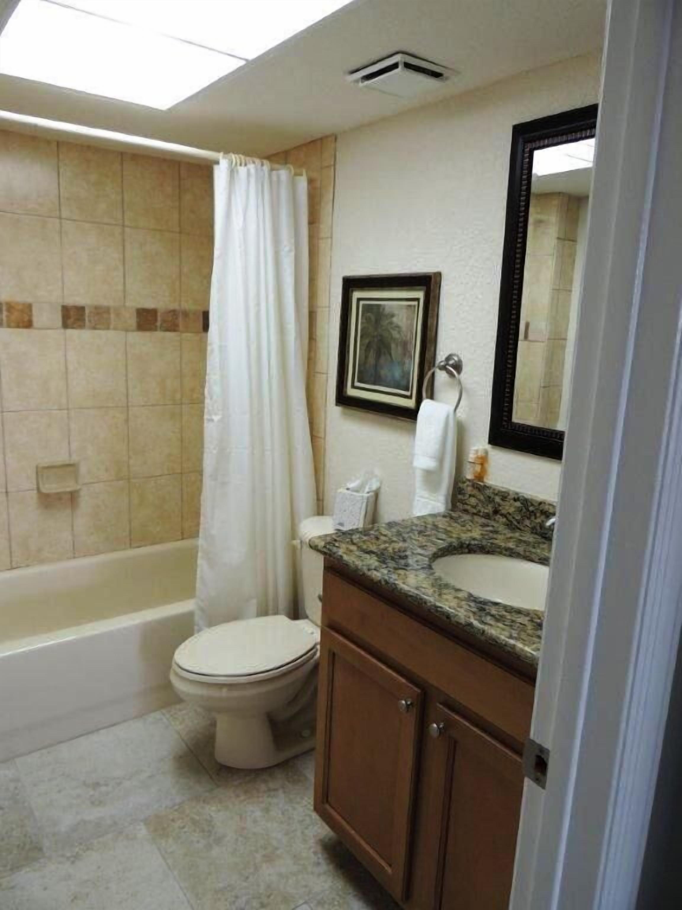 A bathroom with a bathtub, toilet, and vanity with a sink.
