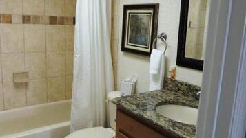 A bathroom with a bathtub, toilet, and vanity with a sink.
