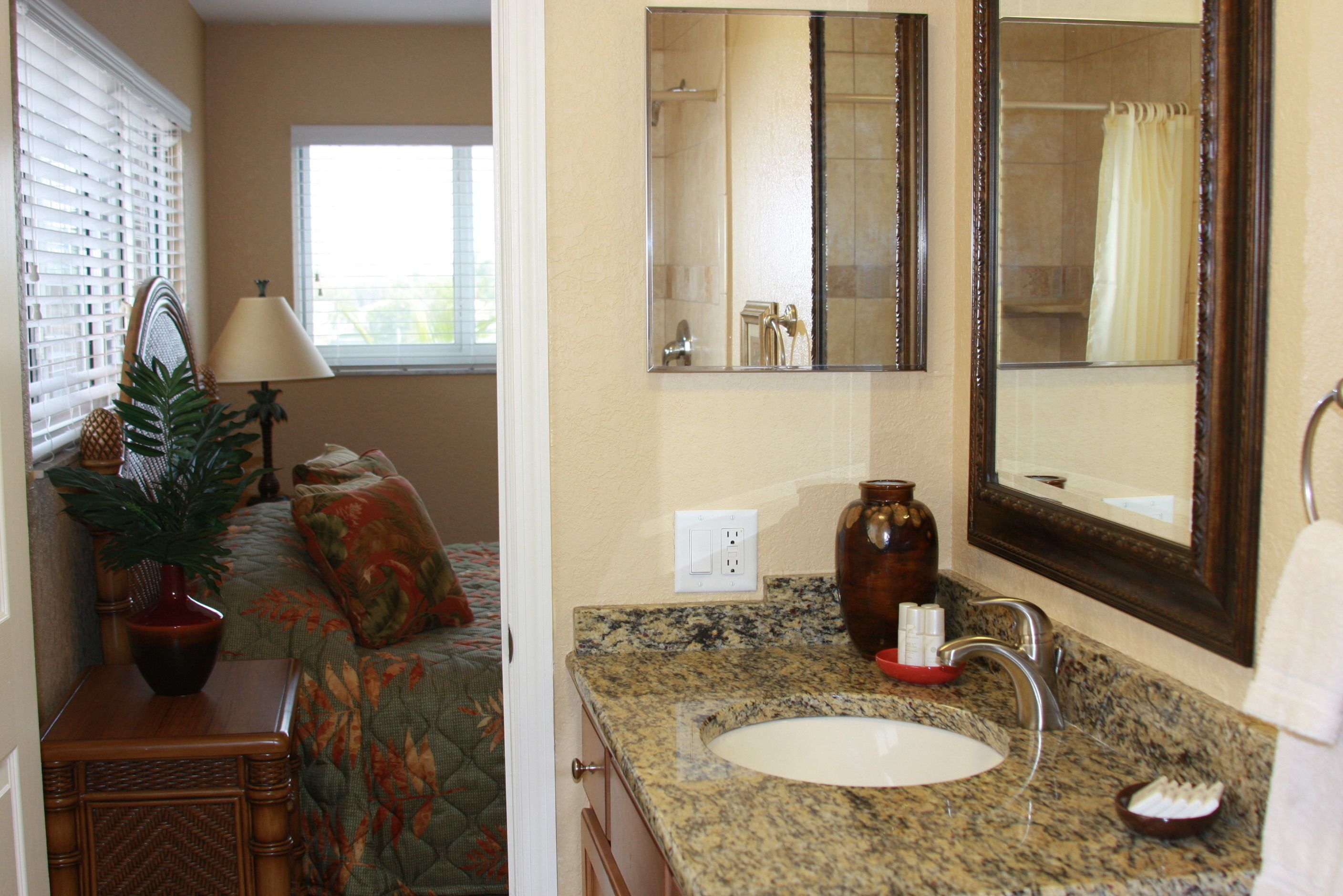 Bagno con piano in granito, lavabo, specchio e doccia.