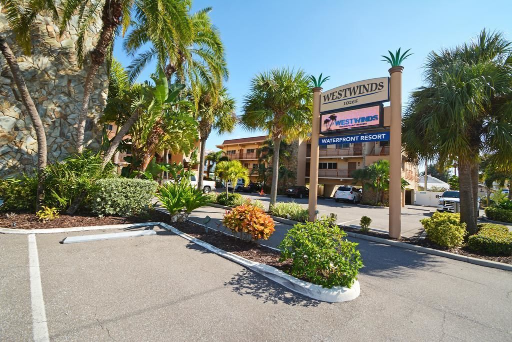 A sign for Westwinds Waterfront Resort with a clear view of the parking lot and surrounding greenery.