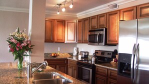 Una cocina con encimeras de granito, electrodomésticos de acero inoxidable, armarios de madera y un florero con flores.