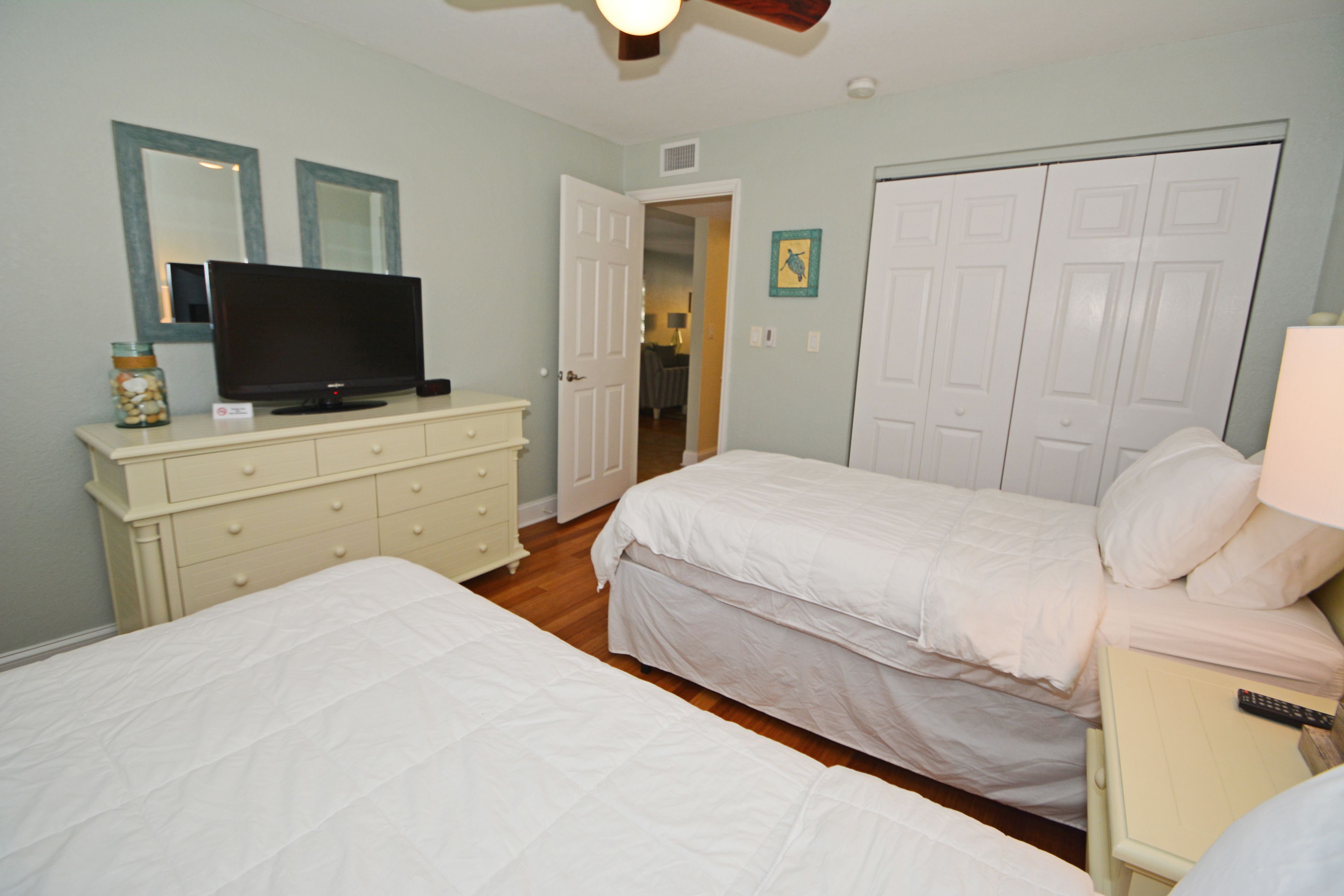 A bedroom with two beds, a dresser, a television, and a closet.