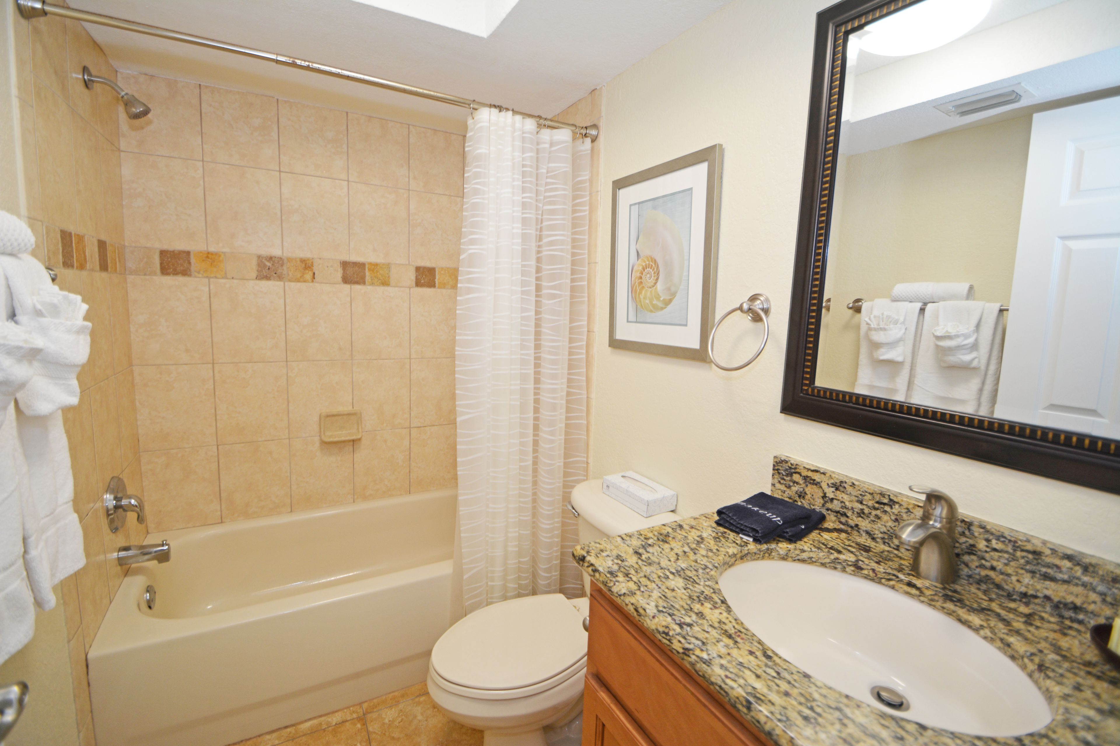 A bathroom with a bathtub, toilet, sink, and a large mirror.