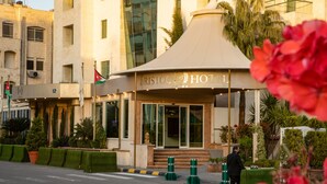 A hotel entrance with a modern design, featuring a prominent sign and a flag. - Bristol Hotel (Amman)