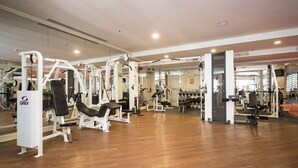 A gym with various exercise machines, mirrors, and a wooden floor. - Bristol Hotel (Amman)